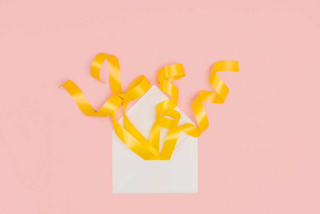 Крупный план открытого белого конверта с желтыми лентами, изолированными на розовом
 - Фото, изображение