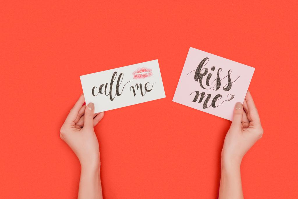 μερική πάνω δείτε πρόσωπο κρατώντας κάρτες με φιλί μου και να μου τηλεφωνήσει επιγραφές και φιλί σήμα που απομονώνονται σε κόκκινο - Φωτογραφία, εικόνα