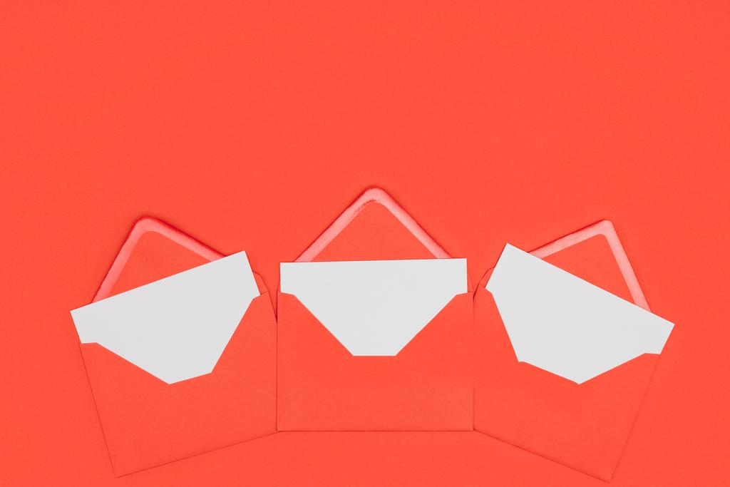 sobres rojos abiertos con tarjetas blancas aisladas en rojo
 - Foto, Imagen