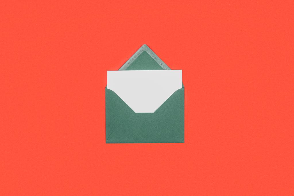 close-up view of green envelope with white card isolated on red - Photo, Image