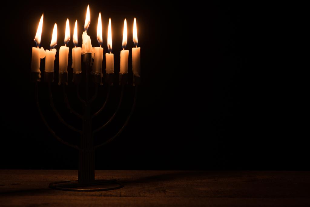 close up view of menorah with candles for hannukah holiday celebration on wooden tabletop on black background, hannukah concept - Photo, Image