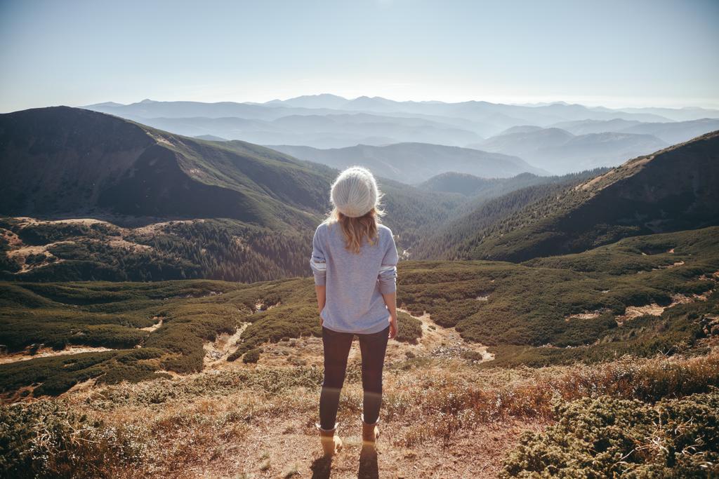 back view of female traveler looking at beautiful mountains on sunny day, Carpathians, Ukraine - Photo, Image