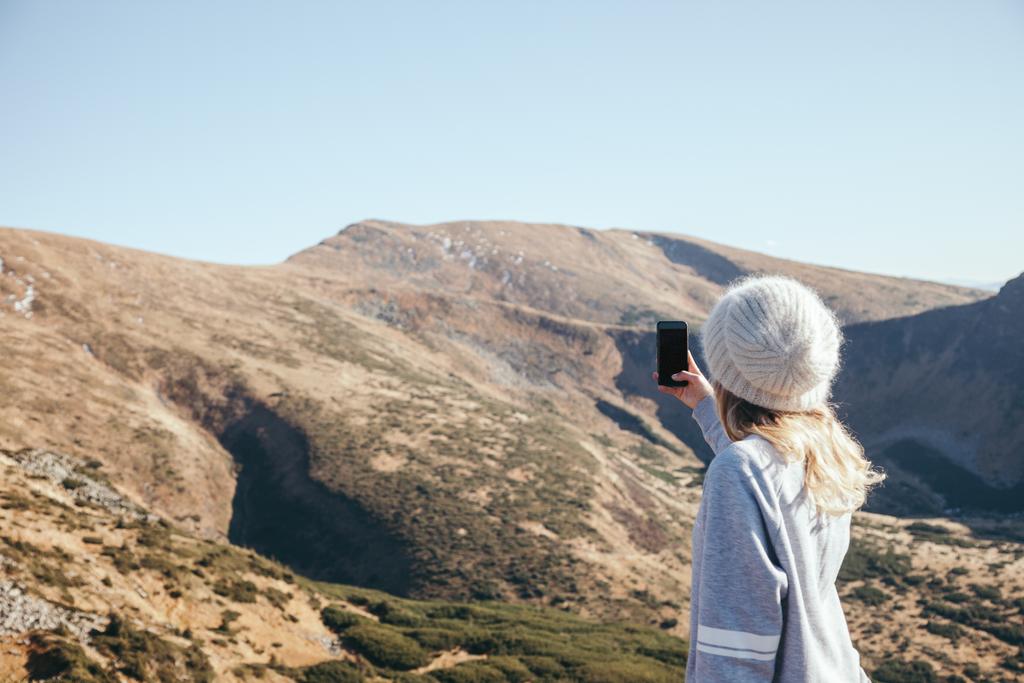 Achteraanzicht van de vrouw nemen foto van berg met smartphone met leeg scherm, Karpaten, Oekraïne - Foto, afbeelding