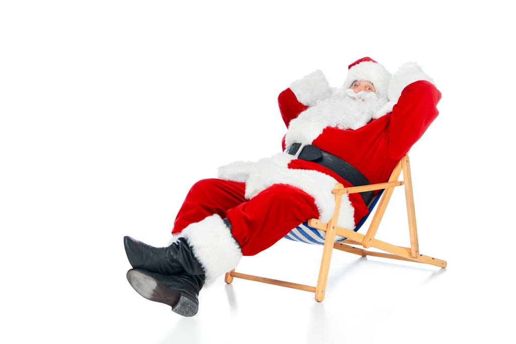 szczęśliwy Mikołaj relaksujący na Krzesło plażowe na białym - Zdjęcie, obraz