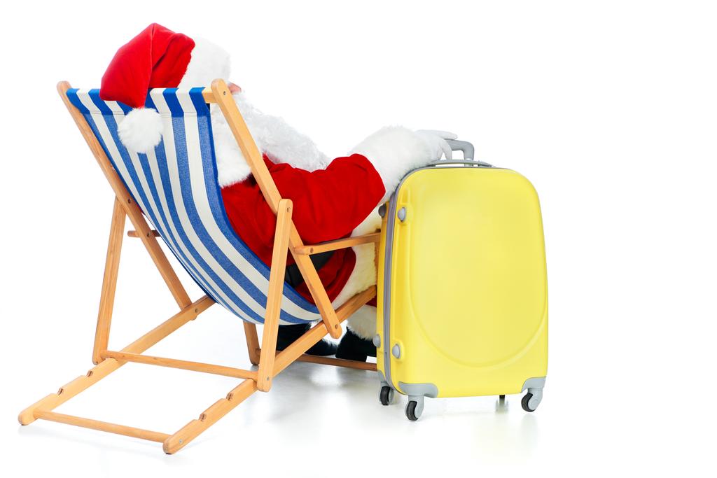 back view of santa claus resting in beach chair with travel bag on white - Photo, Image