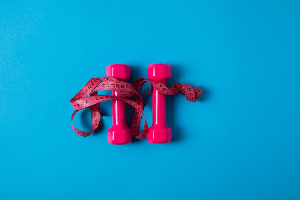 flat lay com fita métrica rosa e halteres isolados em azul, conceito minimalista
  - Foto, Imagem