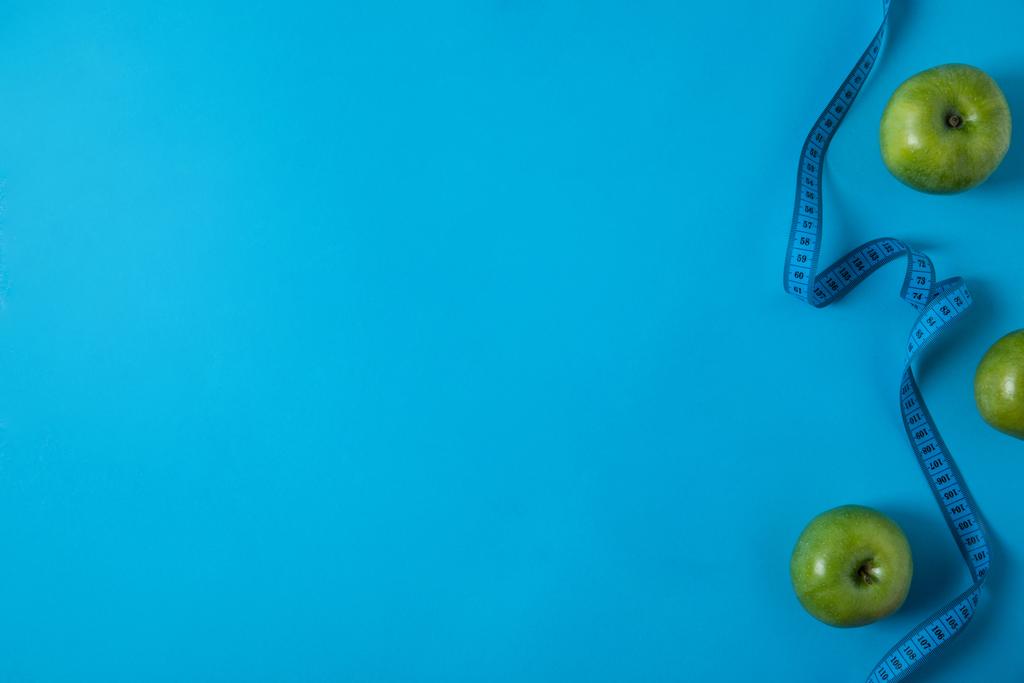 vue de dessus des pommes vertes et ruban à mesurer isolé sur bleu
  - Photo, image