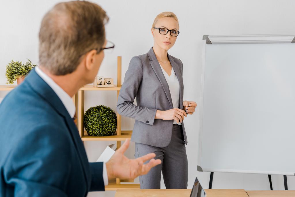 adult man talking to young woman near white board in office - Photo, Image