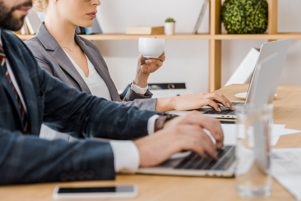 ember használ laptop és nő holding kupa asztalnál hivatalban - Fotó, kép