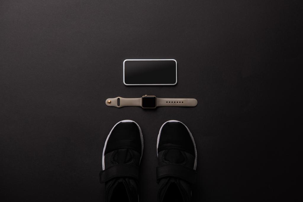 düz lay görücü usulü smartphone, smartwatch ve izole siyah, minimalist kavramı üzerinde ayakkabı ile  - Fotoğraf, Görsel