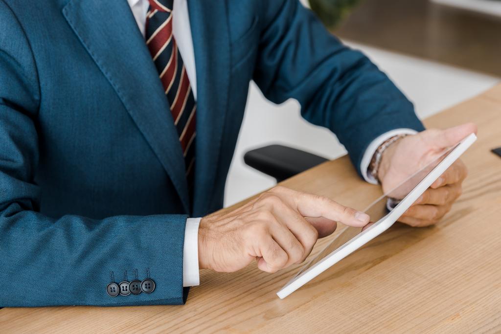 бизнесмен в костюме с помощью цифрового планшета в офисе
 - Фото, изображение