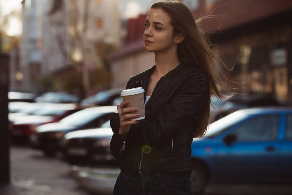 Beautiful woman holding paper coffee cup and enjoying a walk in the city - Photo, Image
