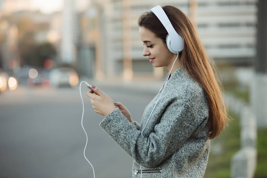 Женщина слушает музыку с наушниками в городе
 - Фото, изображение