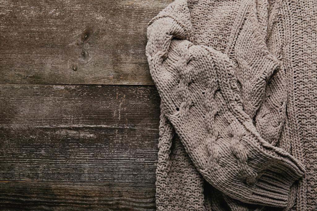 κάτοψη του γκρι πλεκτό πουλόβερ σε ξύλινη επιτραπέζια - Φωτογραφία, εικόνα