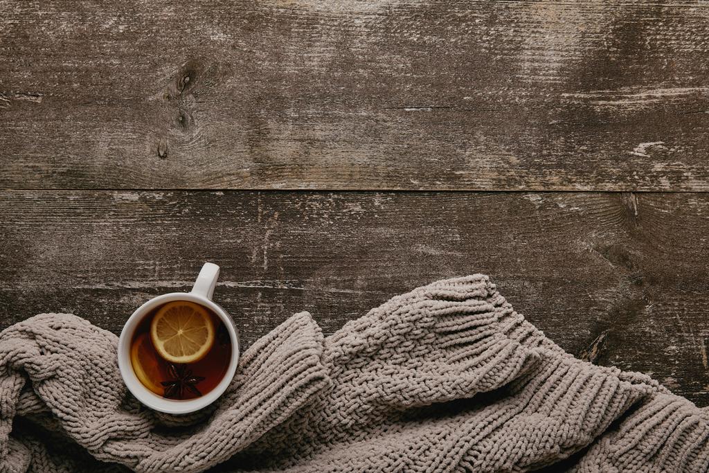 灰色のセーターと木製のテーブルの上のレモン部分とお茶を一杯フラット レイアウト - 写真・画像