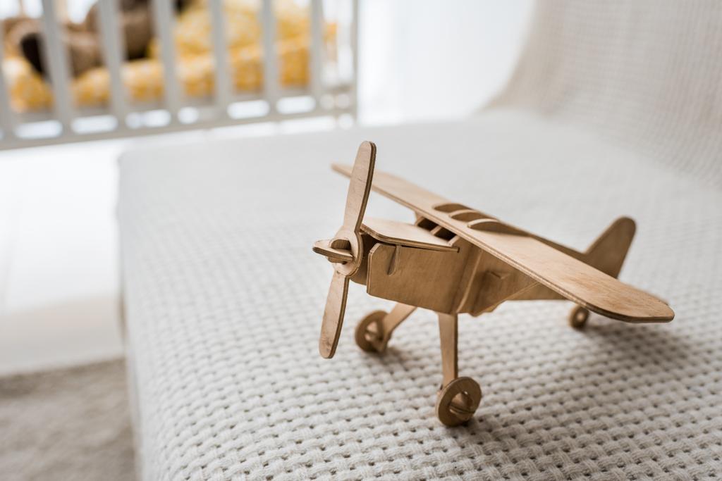 avión de juguete de madera retro en el sofá en la habitación del vivero
 - Foto, imagen