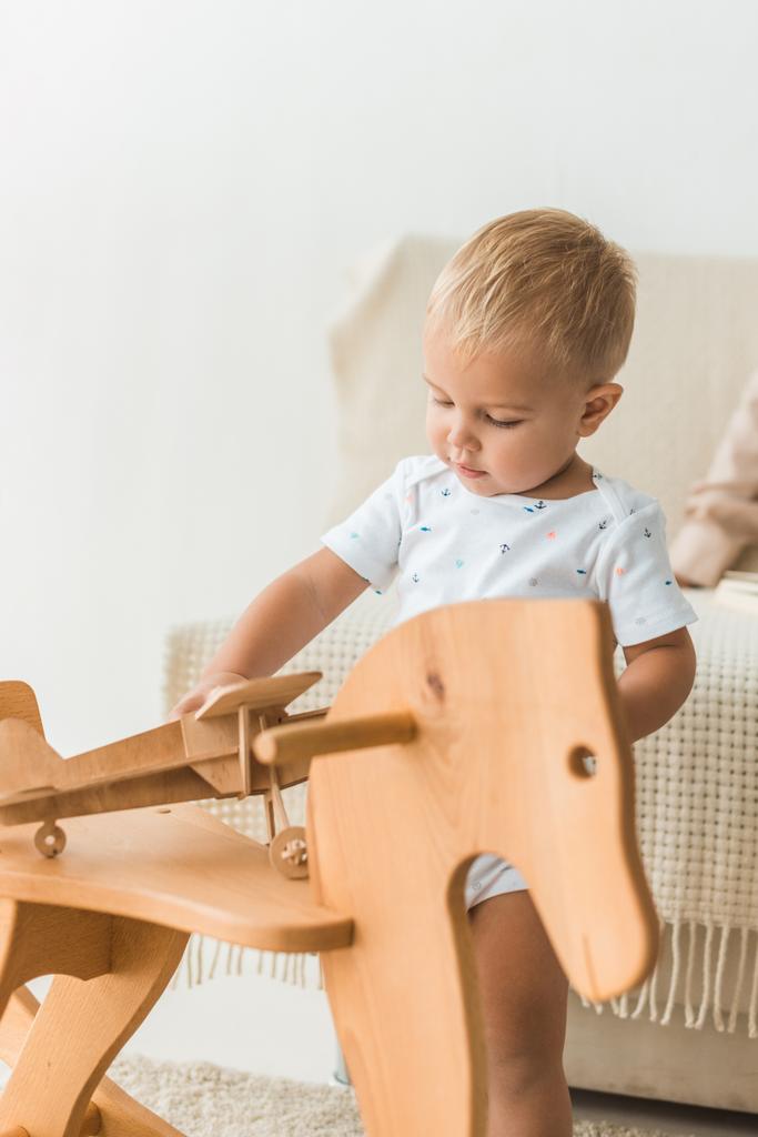 малюк грає з іграшковим дерев'яним конем
 - Фото, зображення