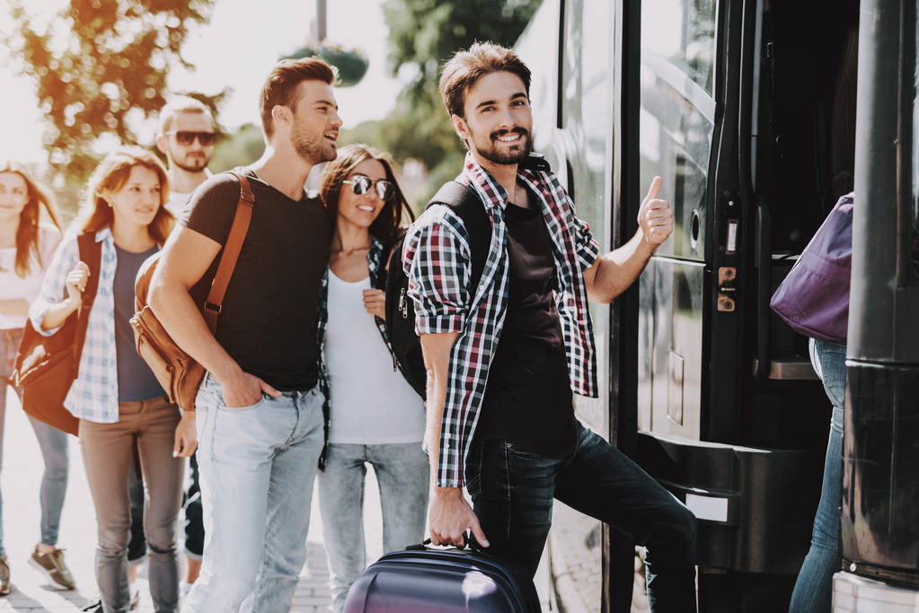 旅行バス上若い人搭乗のグループ。幸せな出張は、入力バスに自分の順番を待っている荷物を保持しているキューに立っています。旅行、観光、人々 の概念。夏の休暇 - 写真・画像