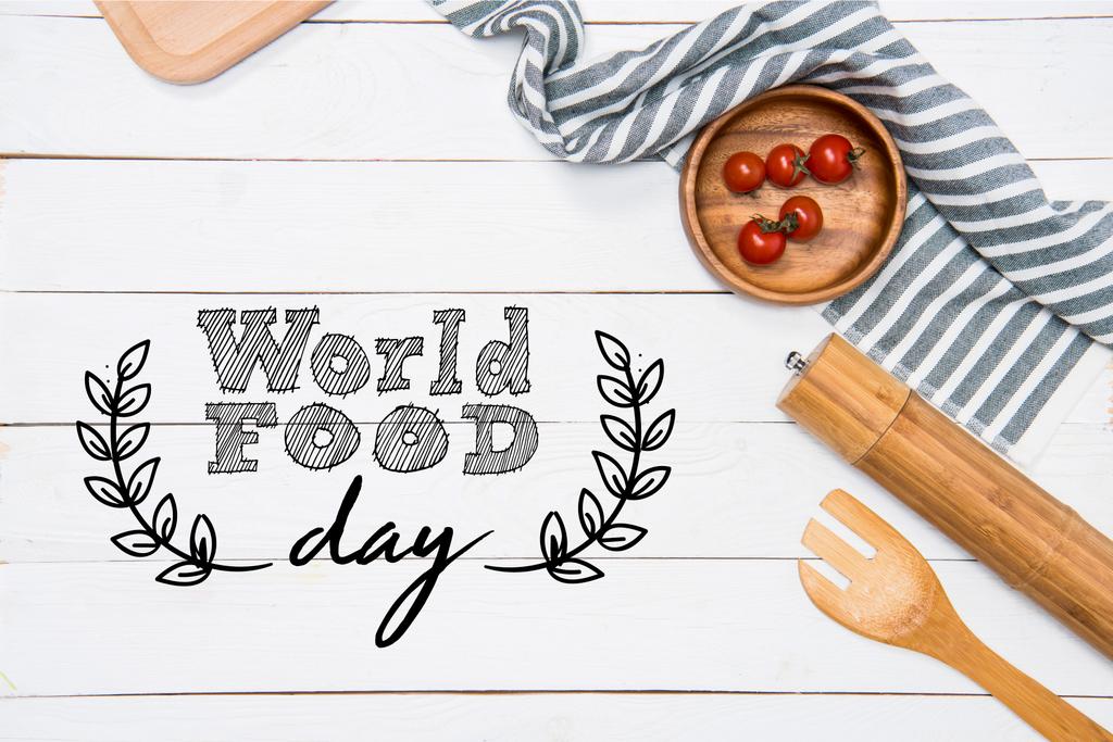 Ντοματίνια με ξύλινη σπάτουλα και μύλο με πανί τραπέζι για επιτραπέζια, τροφίμων παγκόσμια ημέρα επιγραφή - Φωτογραφία, εικόνα