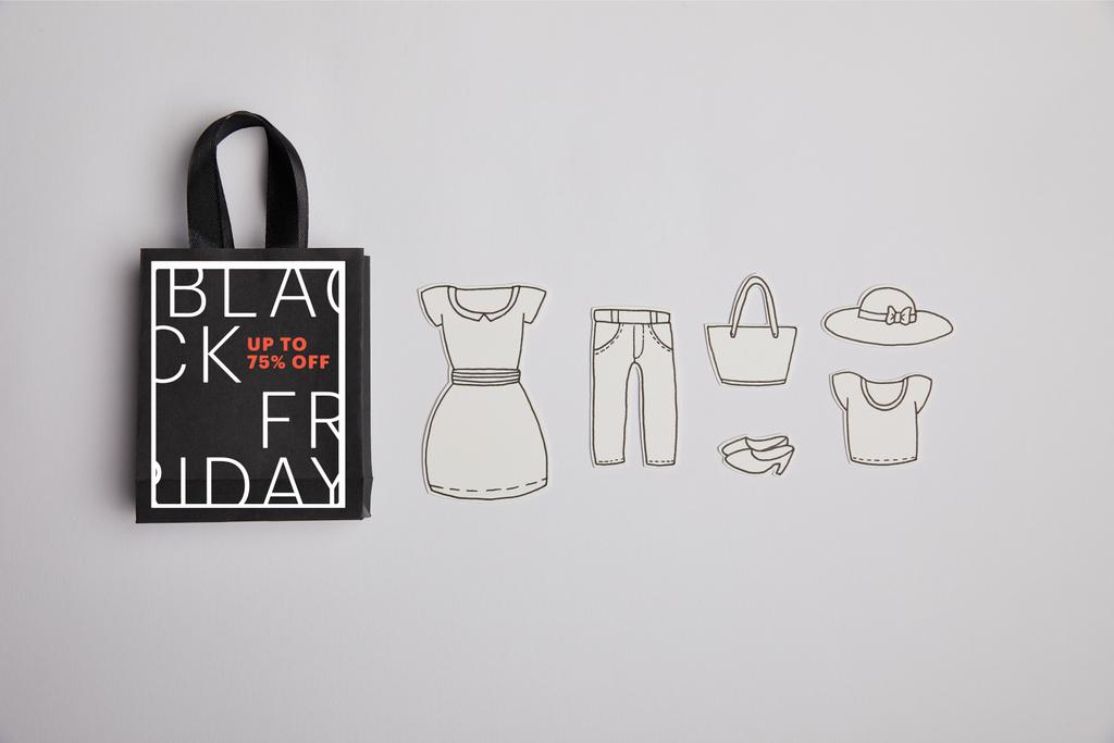 top view of paper bag with black friday sale sign and paper clothes on grey background - Photo, Image