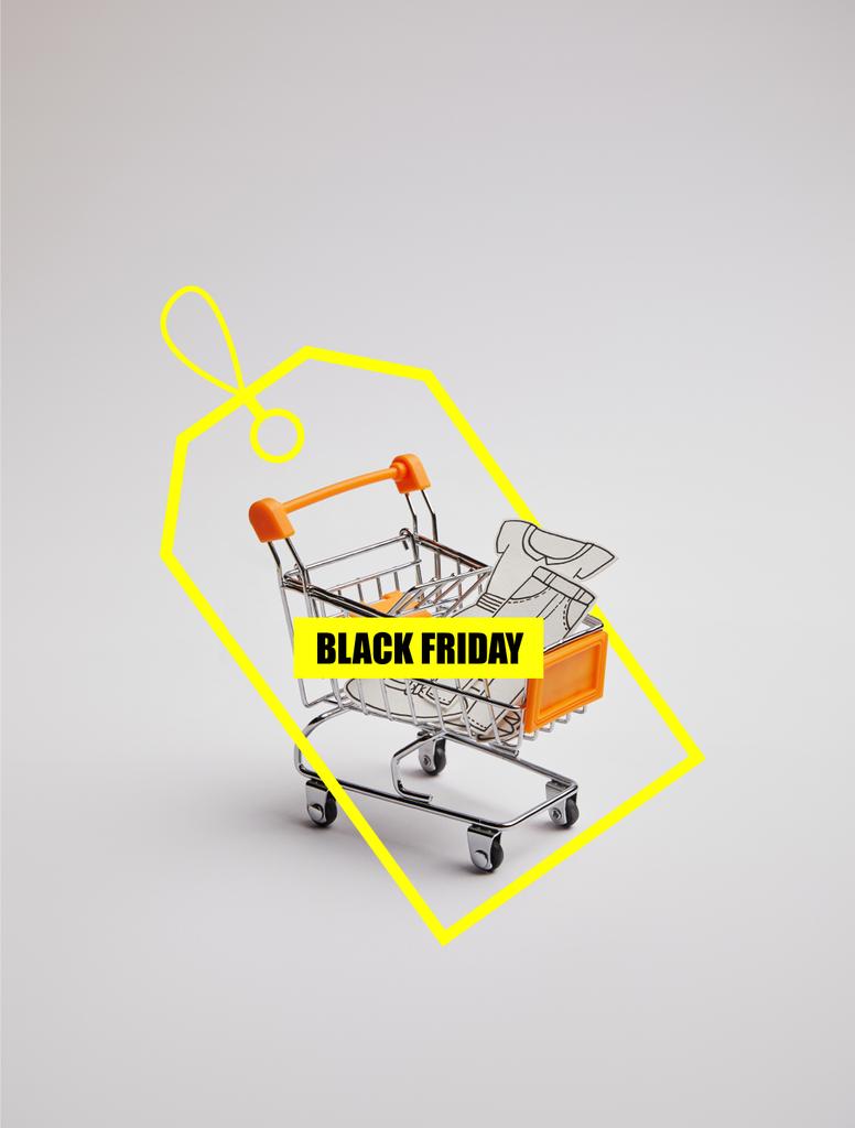 close up view of shopping cart with little goods made of paper on grey background, black friday sale tag - Photo, Image