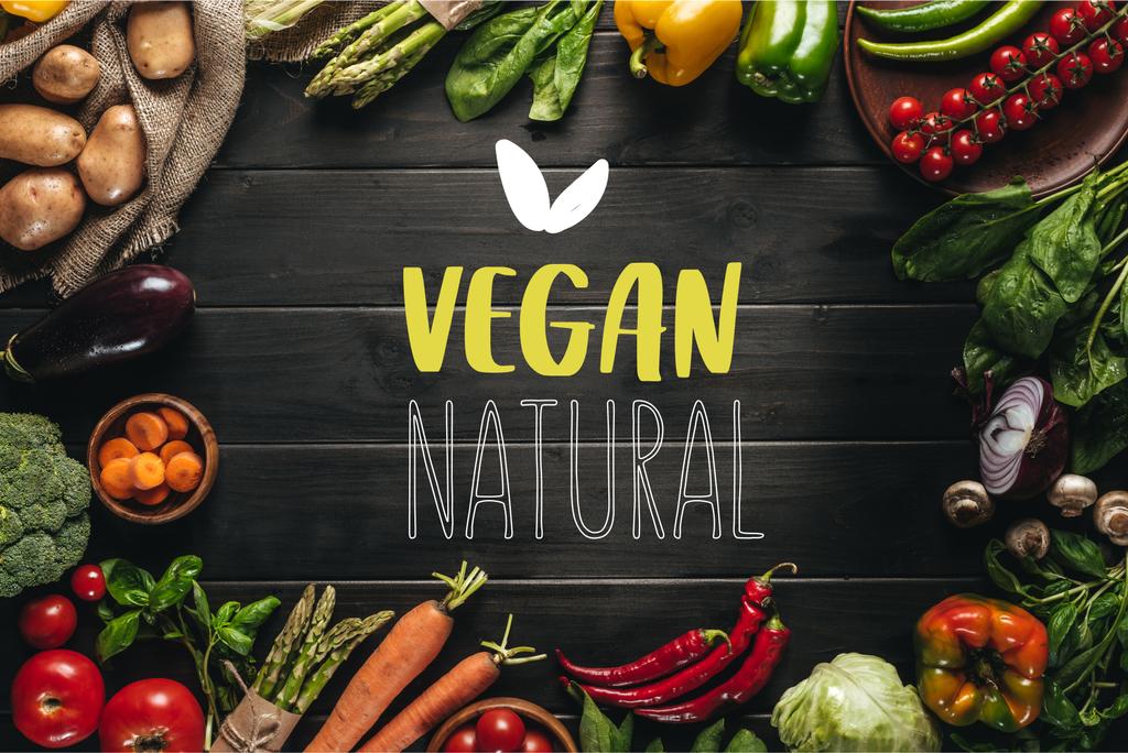Rama organicznych warzyw na zwolnieniu na drewnianym blatem z napisem naturalnej vegan - Zdjęcie, obraz
