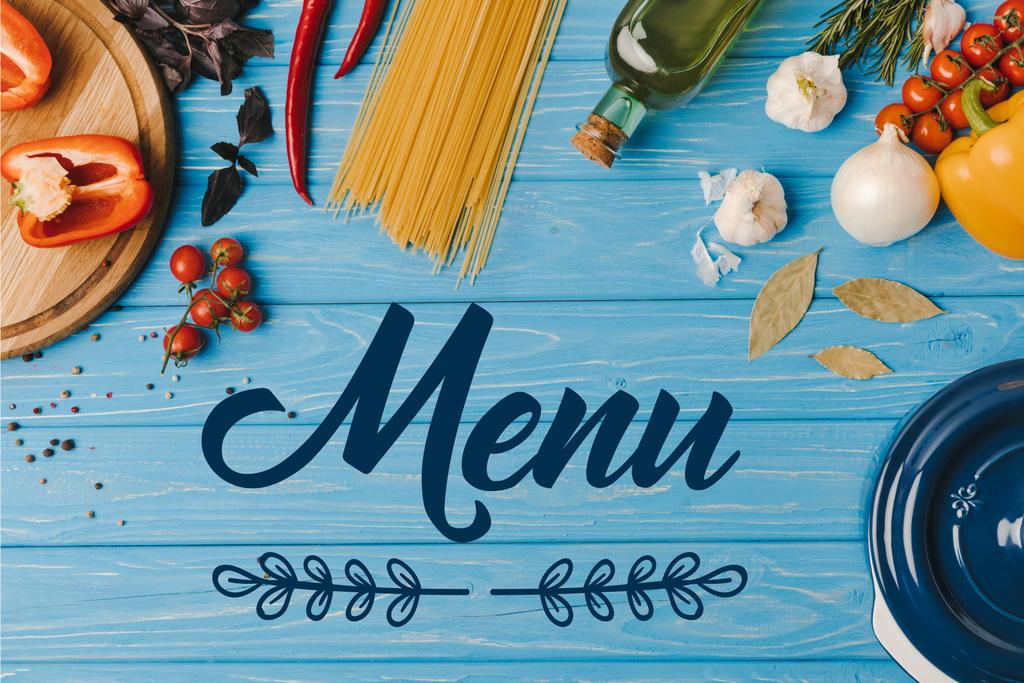 vista superior de los ingredientes para cocinar pasta en la mesa azul, letras de menú
 - Foto, imagen
