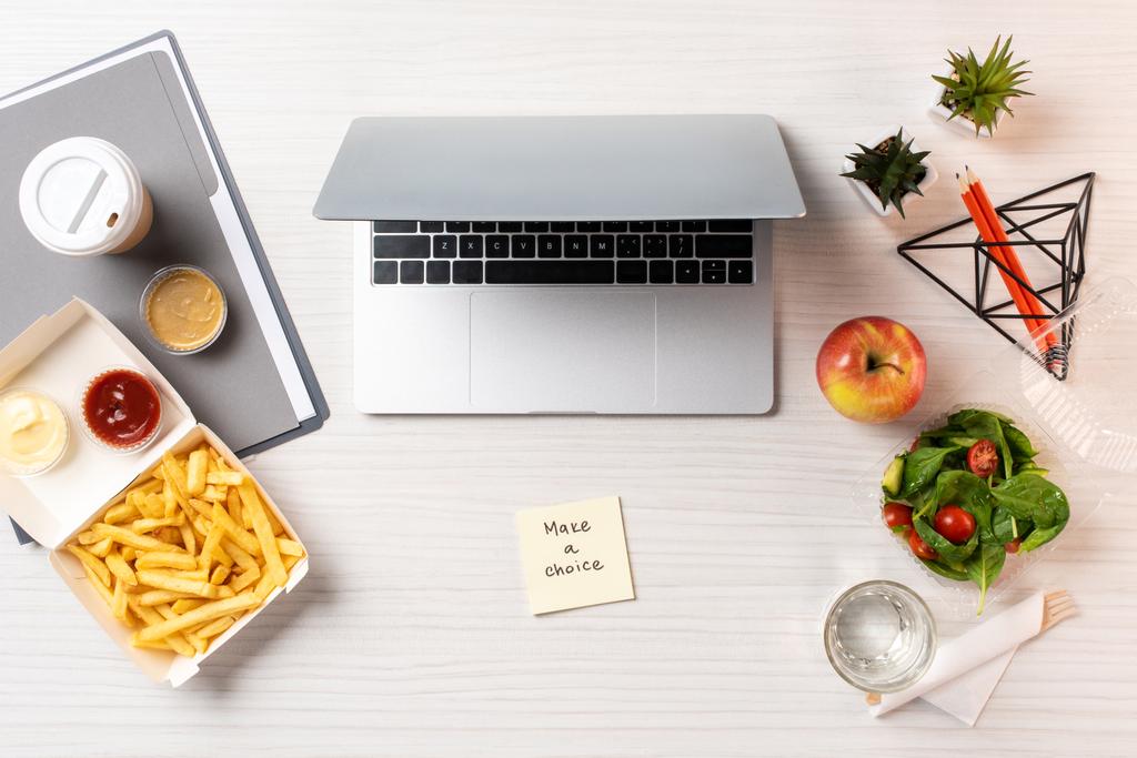 vista dall'alto del computer portatile, carta con iscrizione fare una scelta e cibo spazzatura con cibo sano sul tavolo in ufficio
  - Foto, immagini