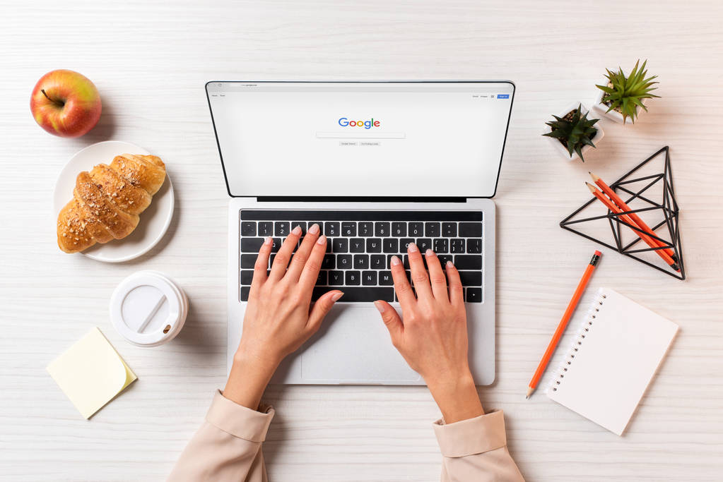 обрізаний знімок підприємець, використовуючи ноутбук із веб-сайтом google за столом з кави, яблуко і круасани      - Фото, зображення