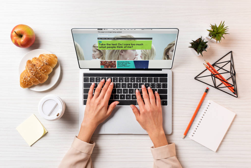 обрізаний знімок підприємець, використовуючи ноутбук з bbc науки веб-сайт столом з кави, яблуко і круасани   - Фото, зображення