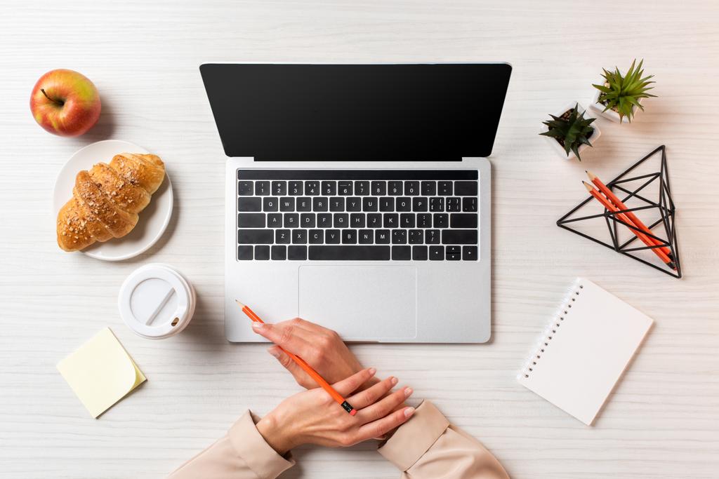 Oříznout záběr ženské ruce, notebook s prázdnou obrazovkou a oběd na stole v kanceláři         - Fotografie, Obrázek