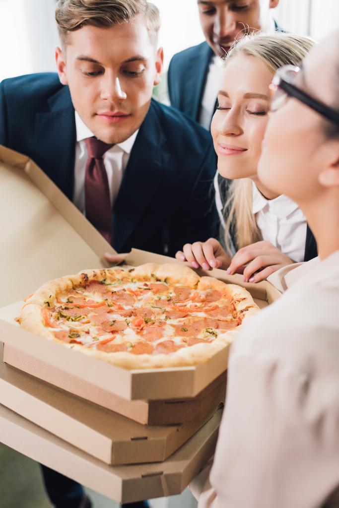 Schnappschuss von jungen Geschäftskollegen, die im Büro leckere Pizza riechen - Foto, Bild