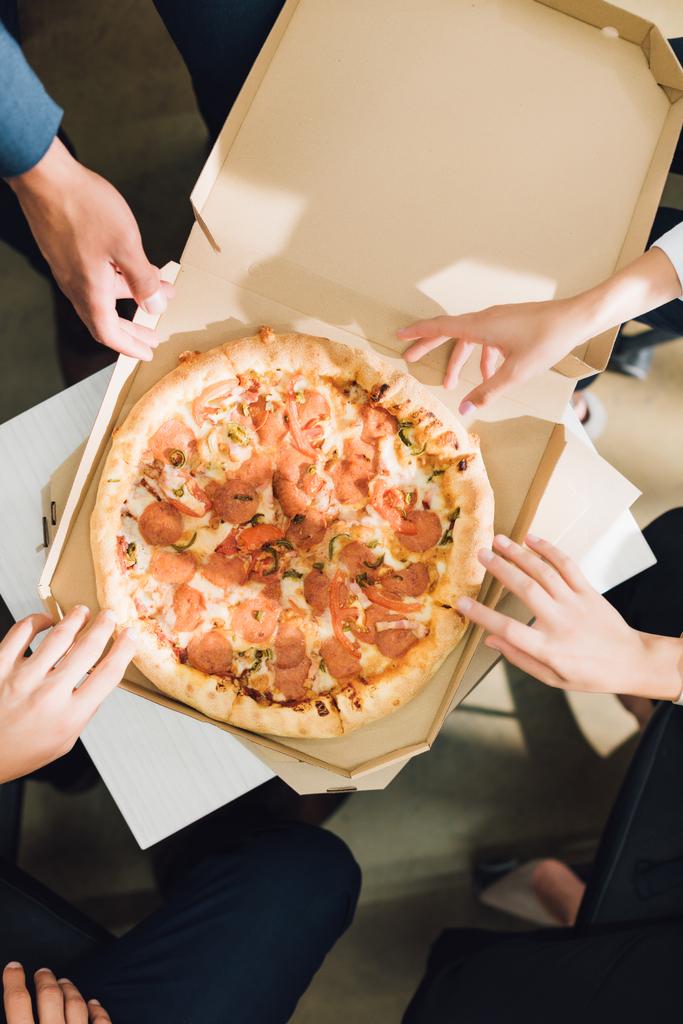 オフィスでピザを食べる若い同僚のショットをトリミング  - 写真・画像