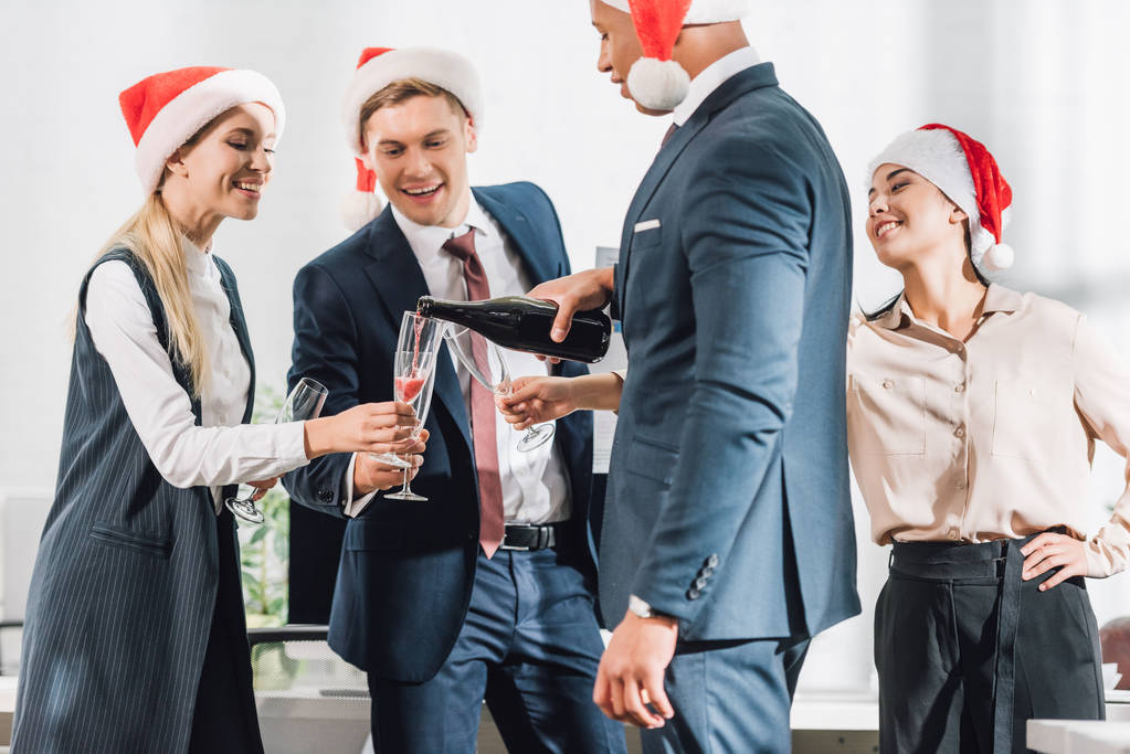 felices jóvenes colegas de negocios multirraciales en sombreros de santa celebrando el año nuevo en la oficina
     - Foto, Imagen