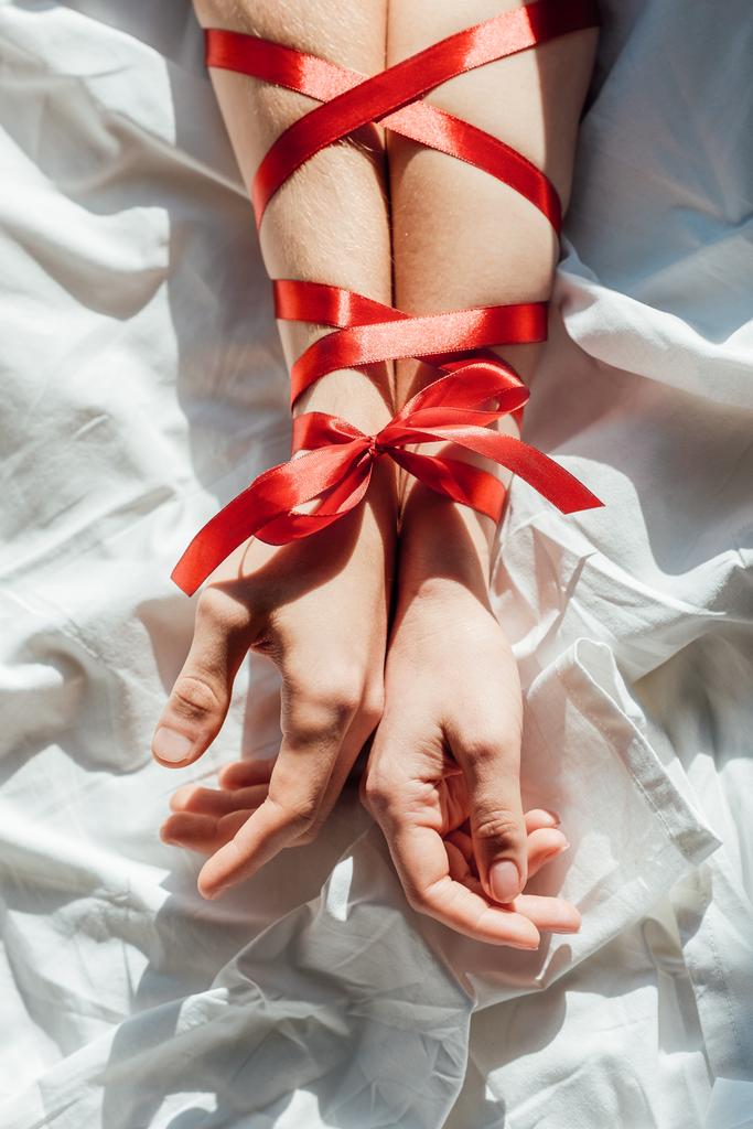 cropped shot of male and female hands tied with red ribbon on bed - Photo, Image