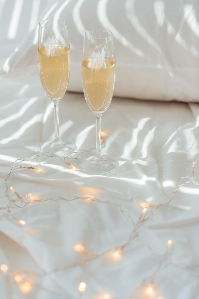 Zamknij widok garland i okulary szampana na łóżku z whire arkusz poduszki i łóżka - Zdjęcie, obraz