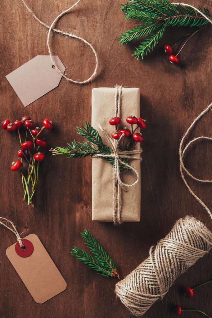plochý ležela s vánoční dárek jedle větve, ozdobné plody, motouzy a značky na dřevěné pozadí - Fotografie, Obrázek