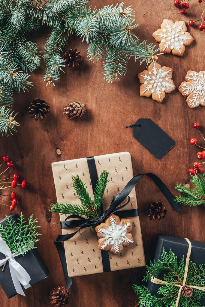 piatto laici con regali di Natale, rami di abete e biscotti su sfondo di legno
 - Foto, immagini