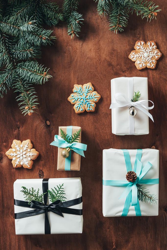 flat lay with christmas gift boxes with fir tree branches and cookies on wooden background - Photo, Image