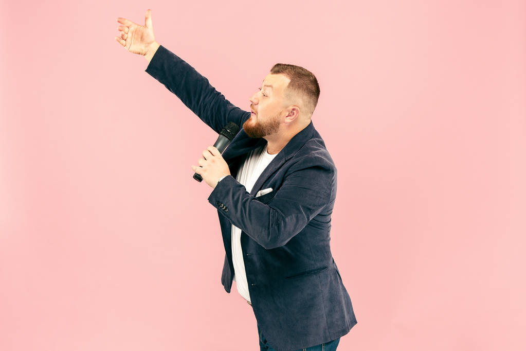 Молодий чоловік з мікрофоном на рожевому фоні, що веде з мікрофоном
 - Фото, зображення