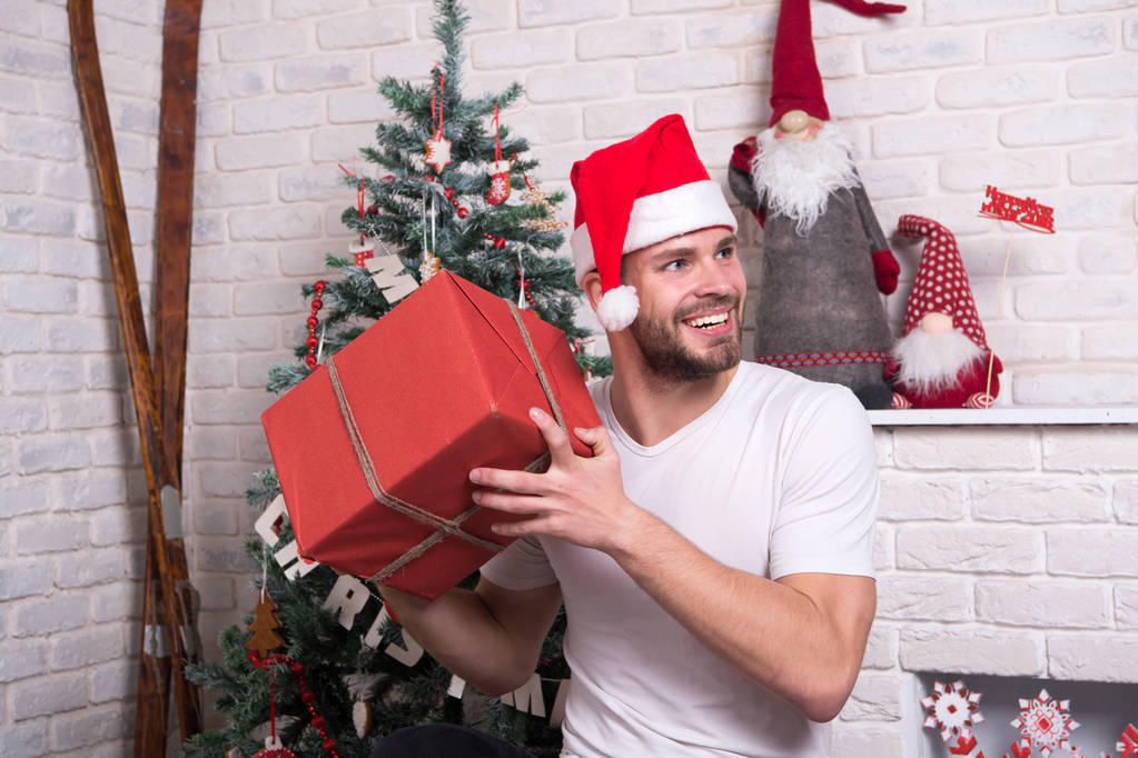 man in santa hat hold christmas present. online christmas shopping. New year scene with tree and gifts. delivery christmas gifts. The morning before Xmas. happy santa man. Office christmas party - Photo, Image
