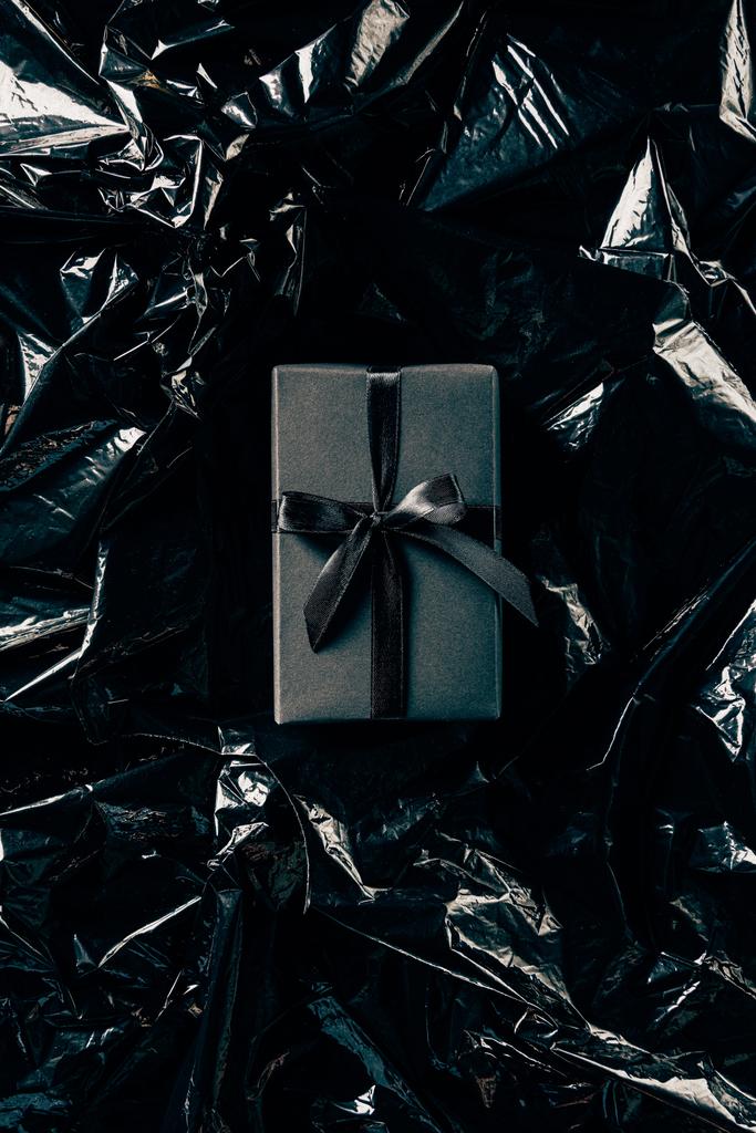 top view of gift box with black ribbon on black wrapping paper backdrop - Photo, Image