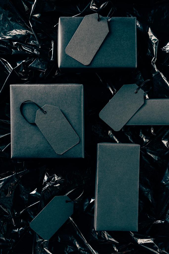 pose plate avec des boîtes noires avec des étiquettes de prix vierges sur fond de papier d'emballage noir, concept du vendredi noir
 - Photo, image
