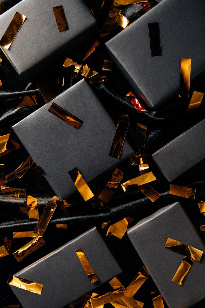 plano con cajas y confeti dorado sobre fondo negro, concepto de viernes negro
 - Foto, imagen