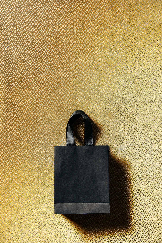κάτοψη του μαύρη τσάντα για ψώνια σε χρυσό βάθος, Μαύρη Παρασκευή έννοια - Φωτογραφία, εικόνα