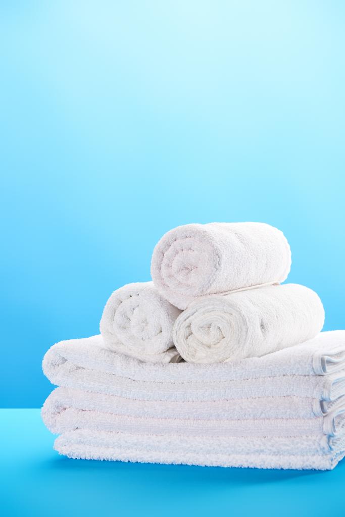 vista de cerca de toallas blancas limpias enrolladas y apiladas en azul
  - Foto, Imagen