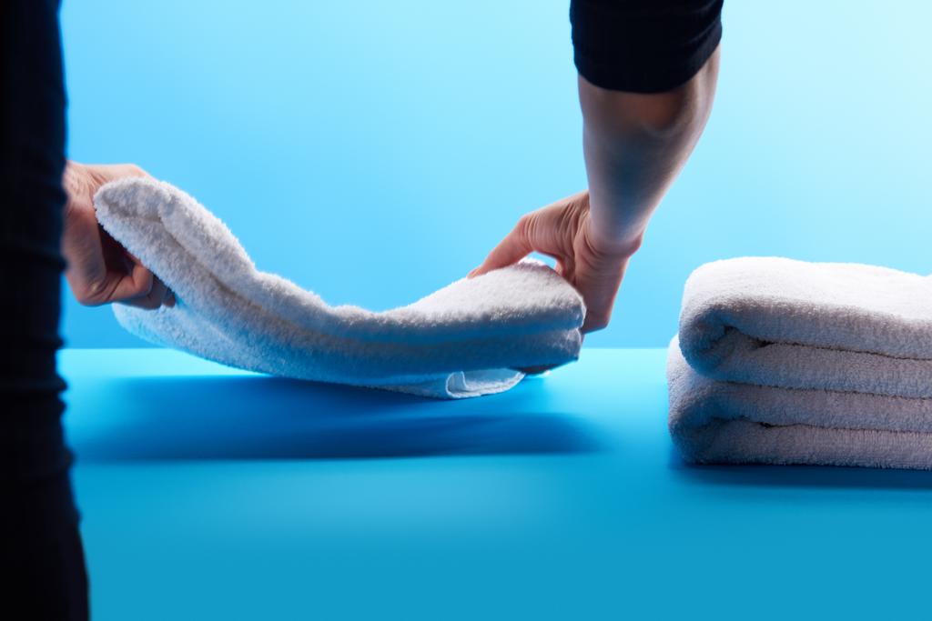 tiro recortado de la persona que apila toallas blancas limpias en azul
 - Foto, Imagen