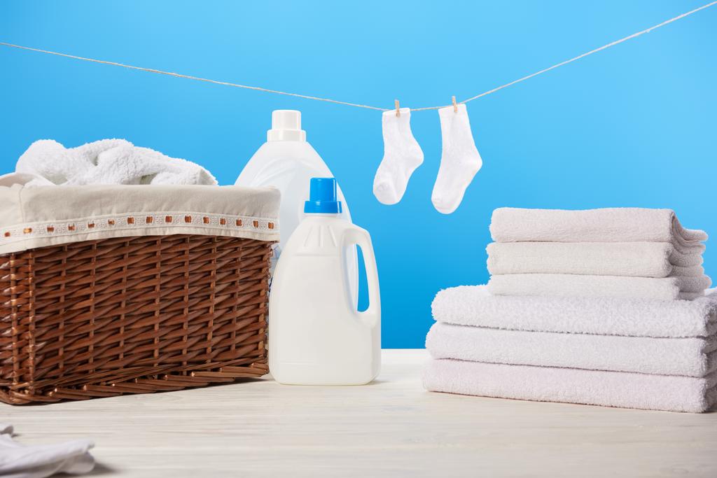 pyykkikori, pesunesteiset muoviastiat, puhtaat pehmeät pyyhkeet ja valkoiset sukat sinisellä köydellä
  - Valokuva, kuva