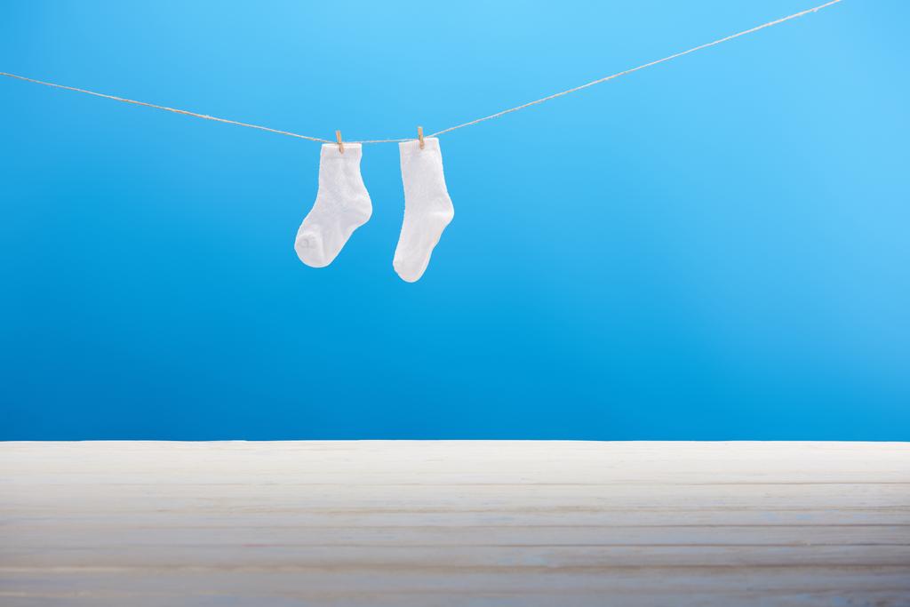 saubere weiße Socken hängen an der Wäscheleine auf blauem Hintergrund  - Foto, Bild