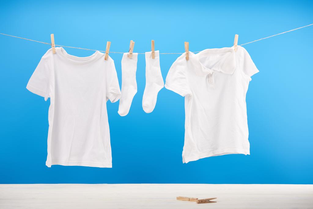 chaussettes blanches propres et t-shirts suspendus sur corde à linge sur bleu
 - Photo, image